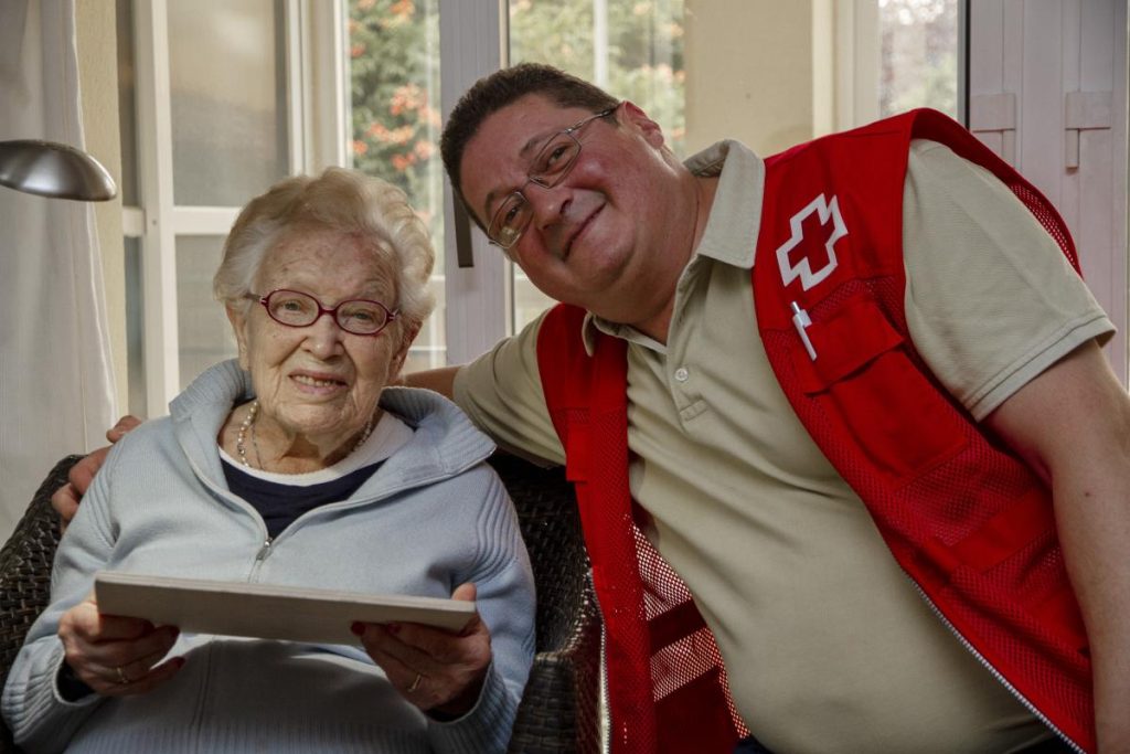 Voluntario cruz roja posando con una Anciana sonriente